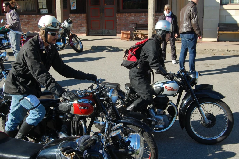 motorcycles parked on the street near some people standing around