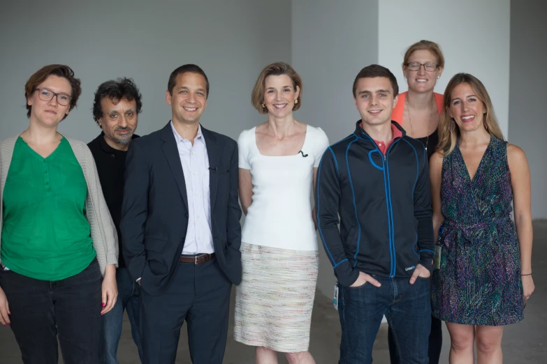 several people stand together in front of a wall