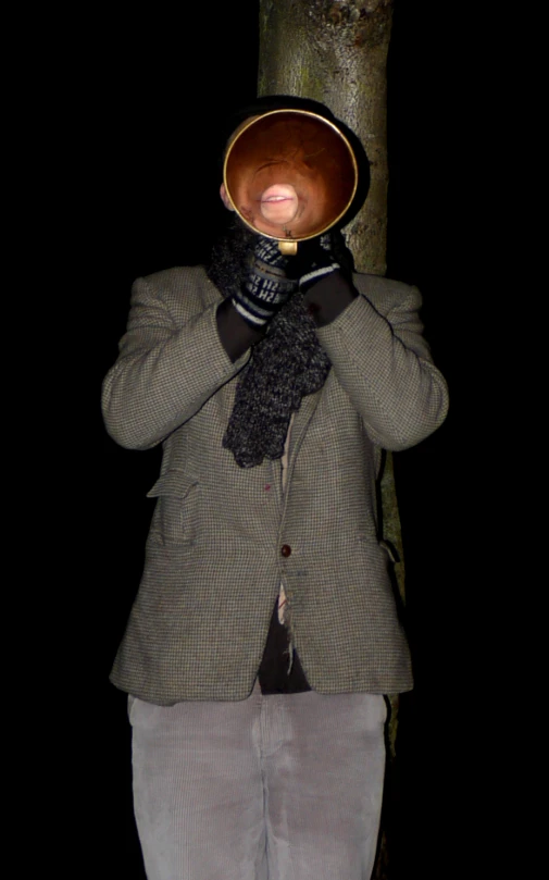 man covering face with glove under tree, dark background