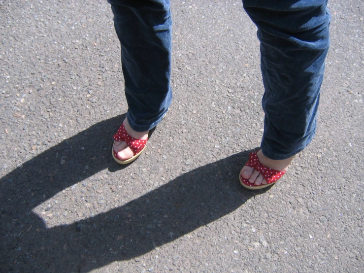 a person standing on cement with their feet and red shoes on