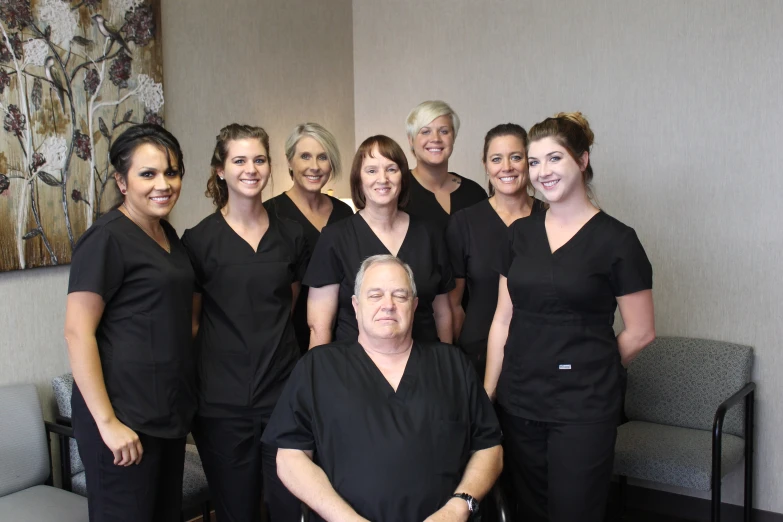 a large group of smiling, well - dressed dental staff pose for a po