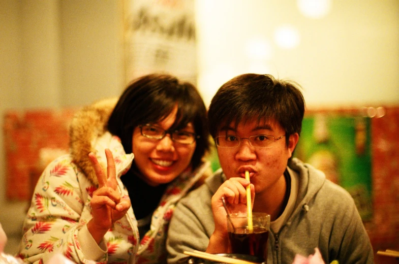 a man and woman smiling while drinking in front of some tables