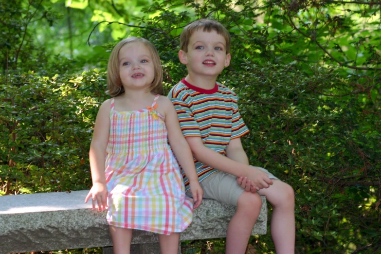 two children on a concrete bench and a tree