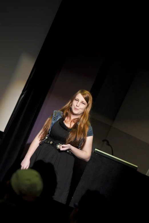 a woman stands in front of a black backdrop