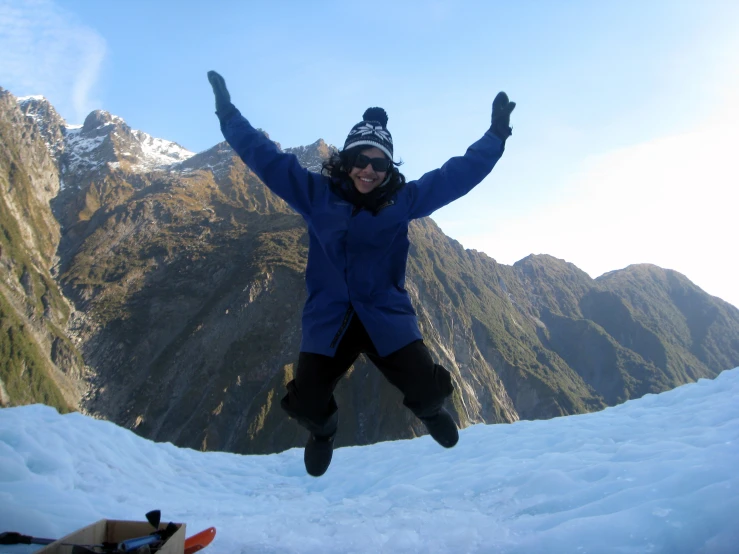 woman jumping in the air on top of a snow covered mountain