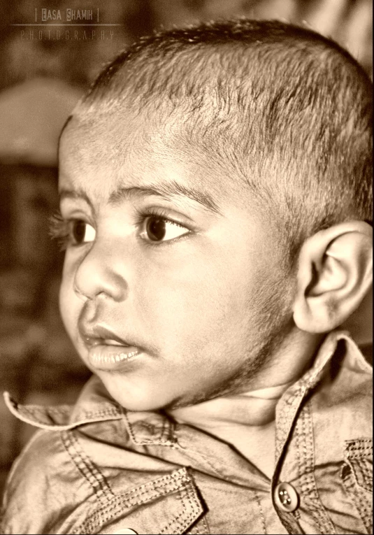 a little  in front of a brick wall looking pensive