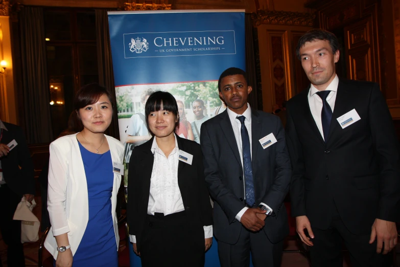 group of four people posing for a picture in front of a sign