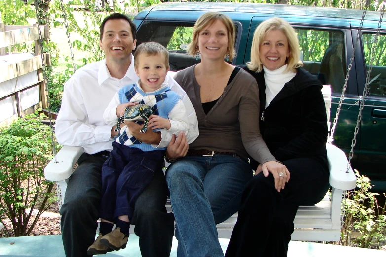 three people pose for a family portrait as they sit in front of their truck