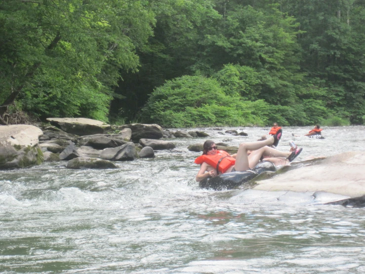 people raft down a small stream in the mountains