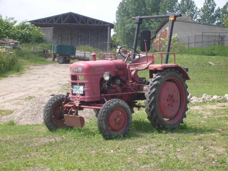 a large, old red tractor sitting in a grassy field