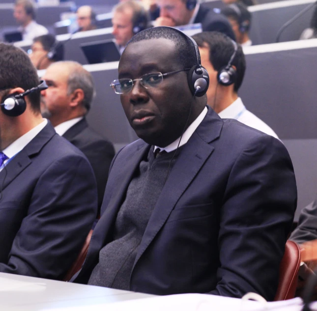 men in business attire wearing ear phones are sitting at a table