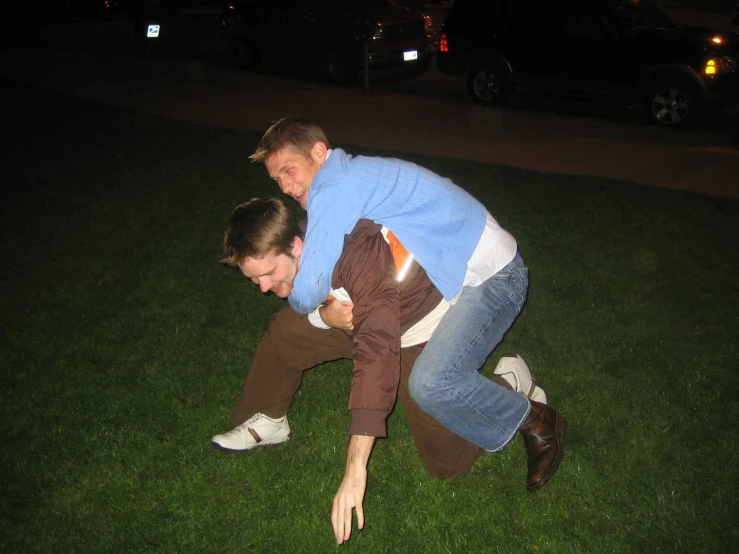 two young adults are playing in the grass