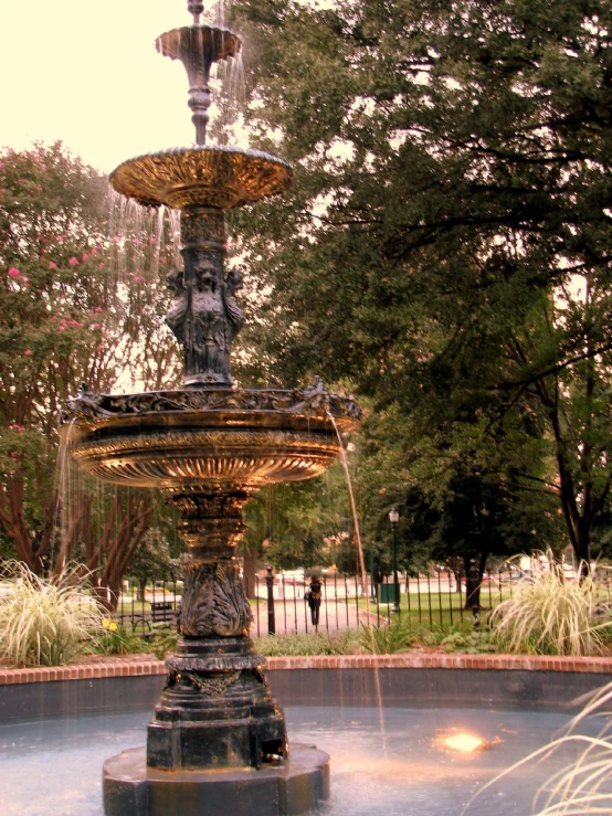 a water fountain in a park is surrounded by trees