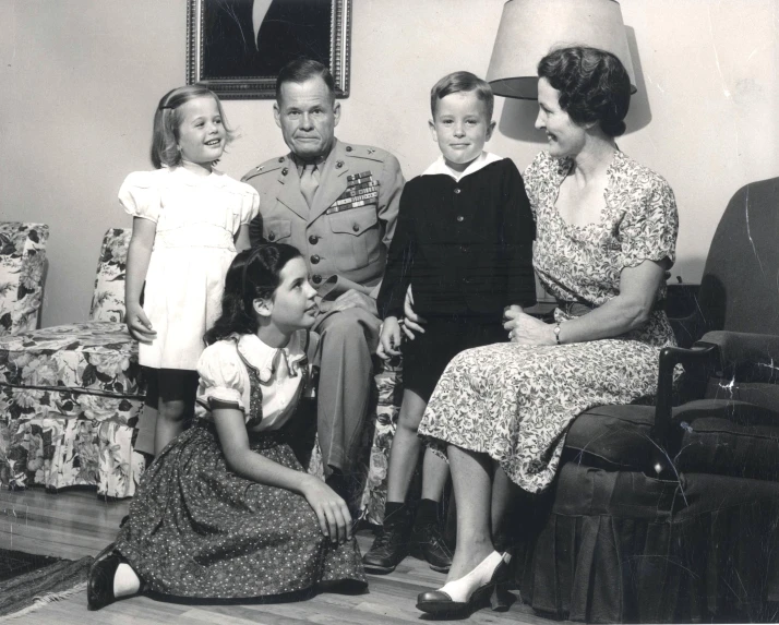 an old po shows a woman sitting in a chair next to her two children and two adults