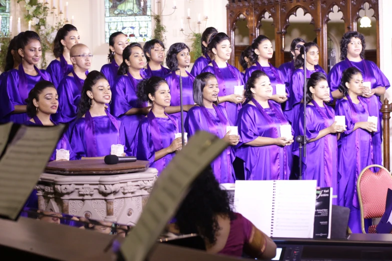 a choir with purple dresses stands near a stage