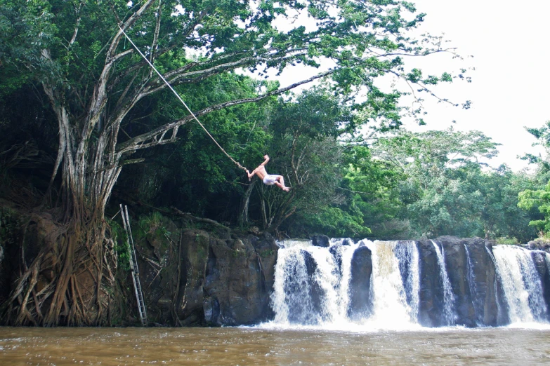 someone is riding a zip line next to a waterfall