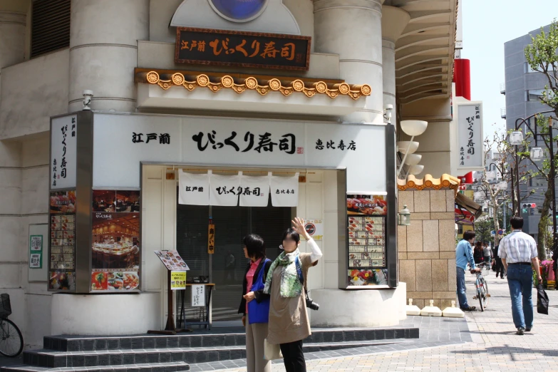 a woman taking a picture of a storefront on the side walk