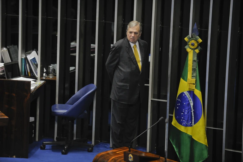 a man standing next to a flag and a wooden desk