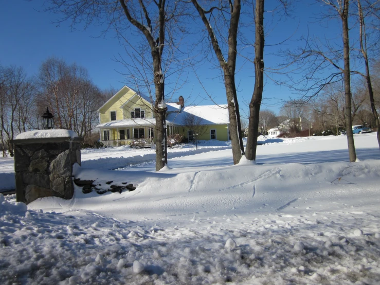 a house is covered with snow beside some trees