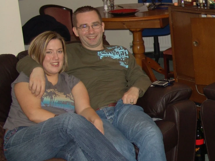 a woman sitting on the lap of a man who is sitting on a brown couch