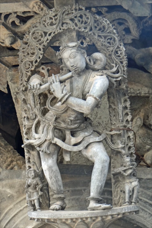 statue on rock with fluteed musician in foreground