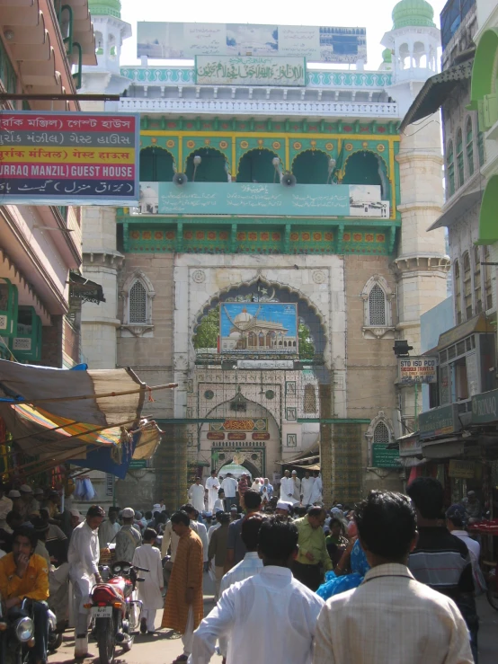 a group of people walking down the street in front of an oriental gate