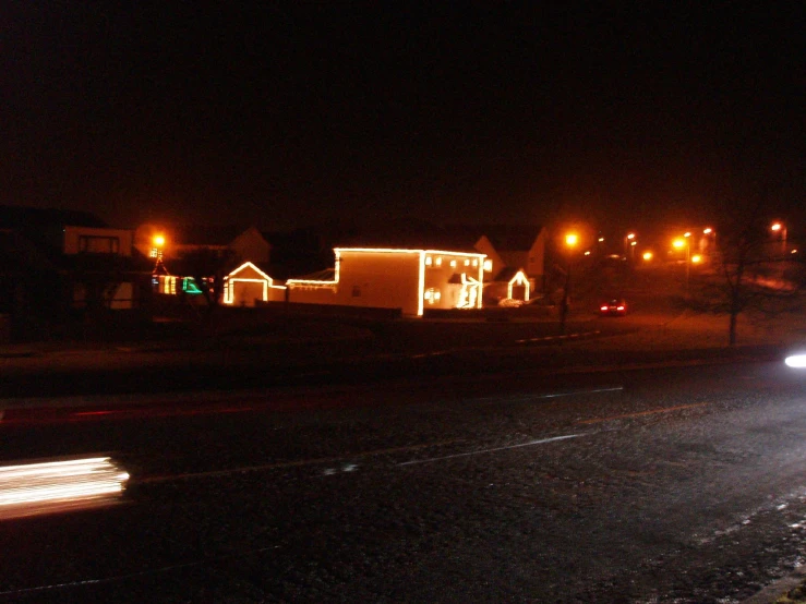 a city street at night, lit up with lights and houses