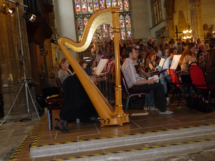 a woman playing a harp in front of a large group of people