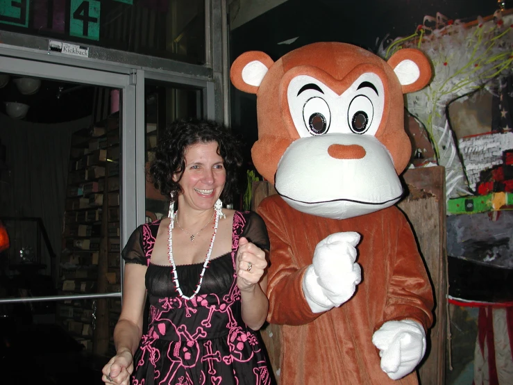 woman posing next to large mascot of a monkey