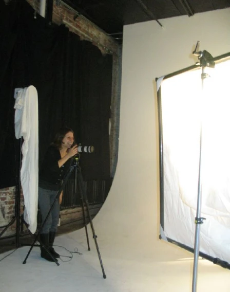 woman in grey sweater with camera in front of camera set up
