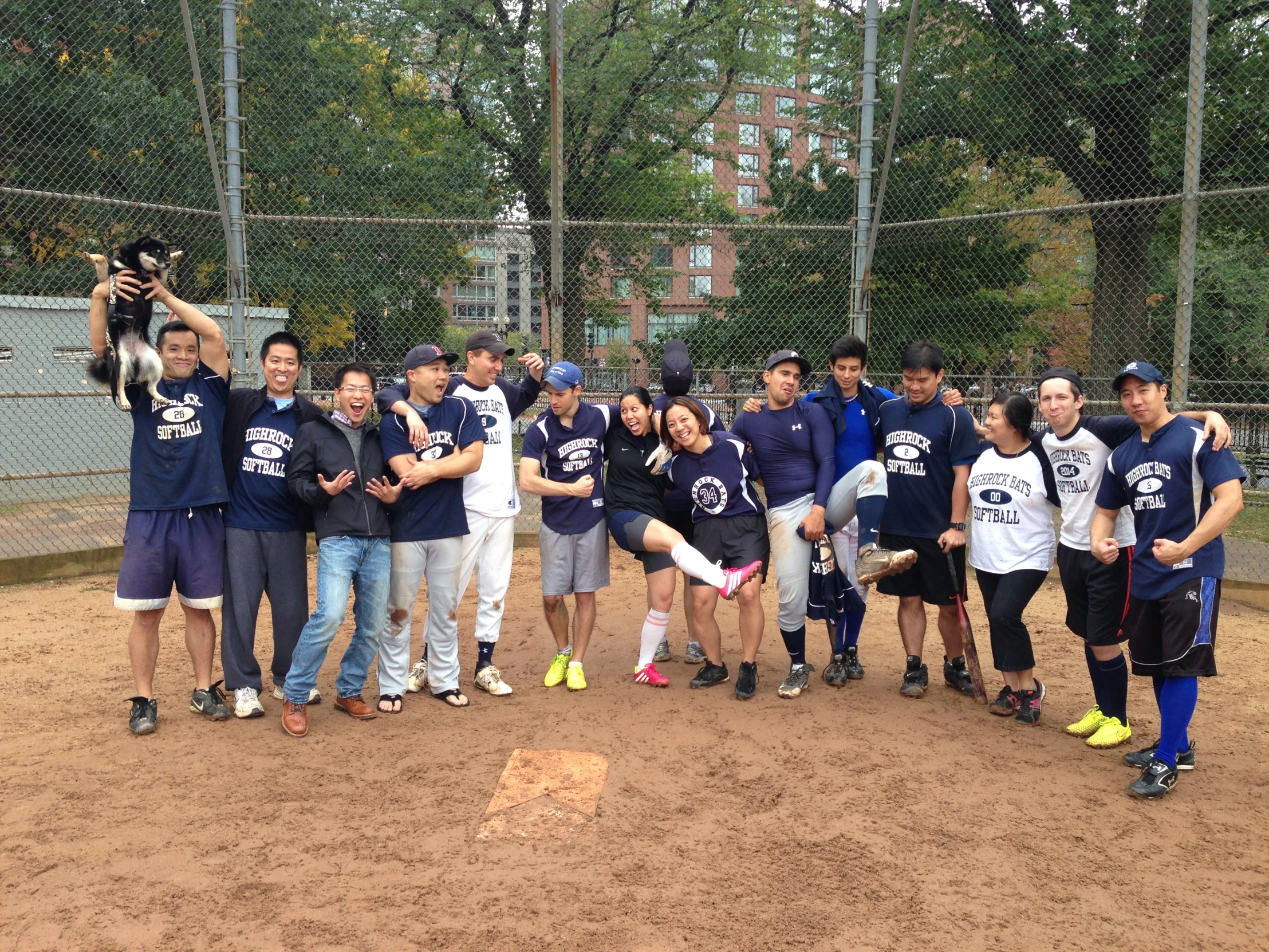 group of people holding up a trophy at a baseball field