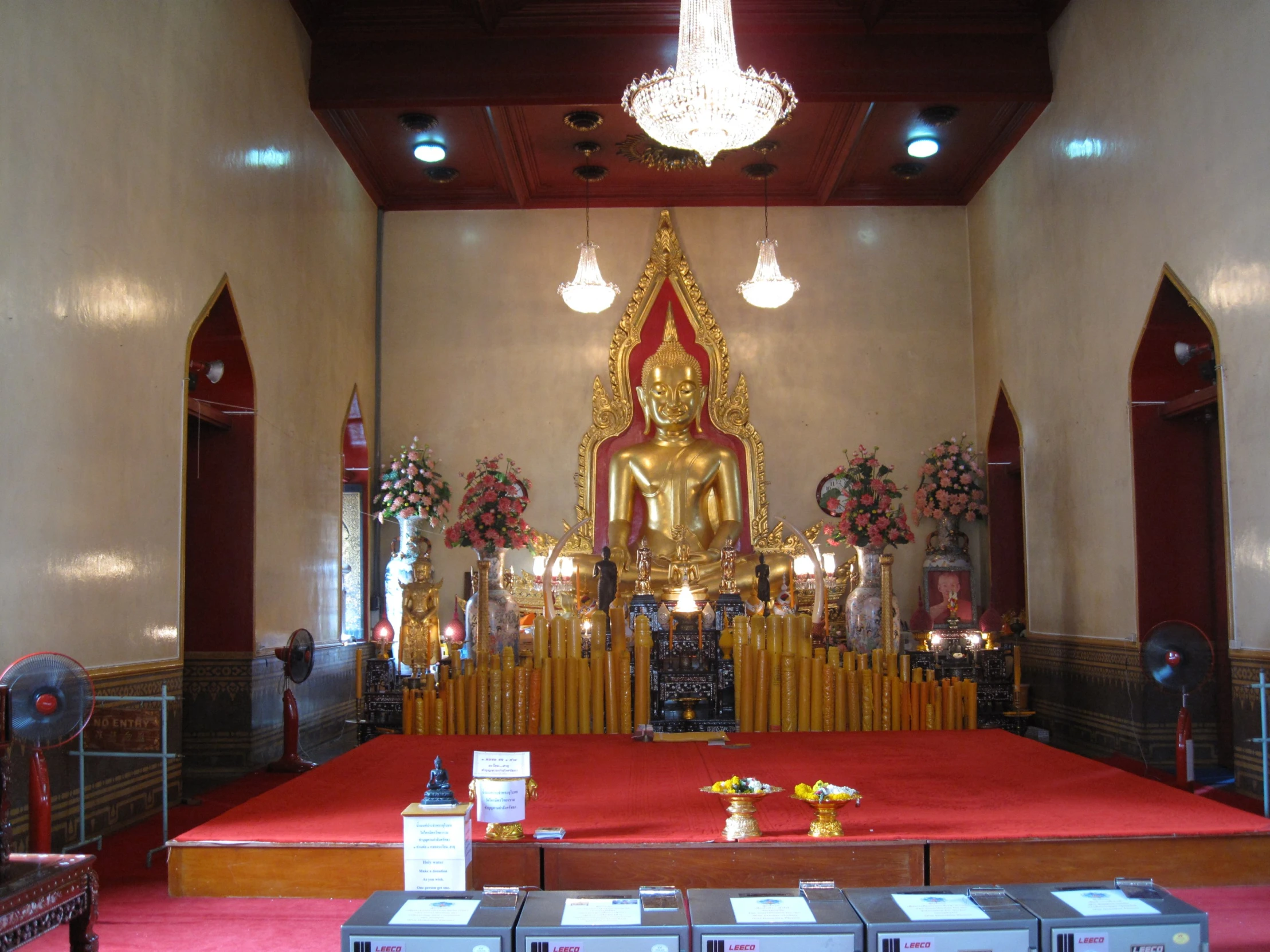 an empty church with wooden chairs, red carpet, and gold alterp