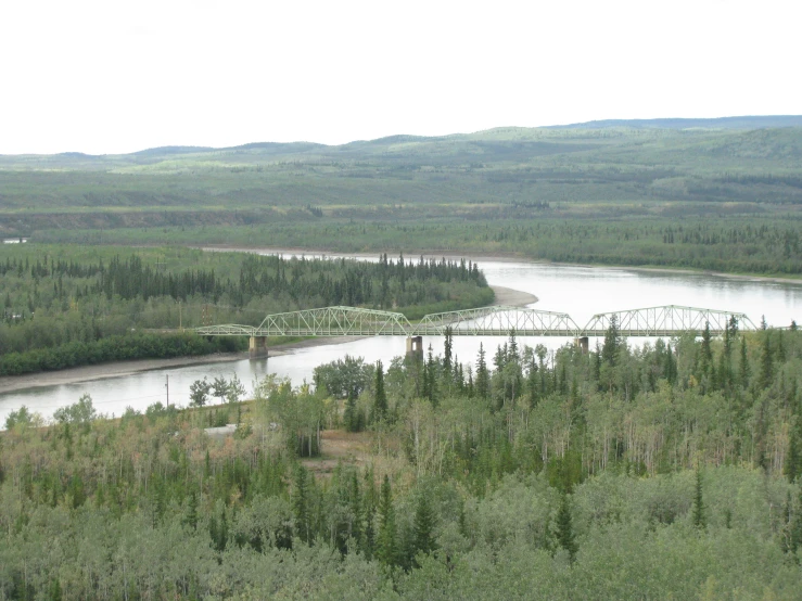 a large river surrounded by green trees in the mountains