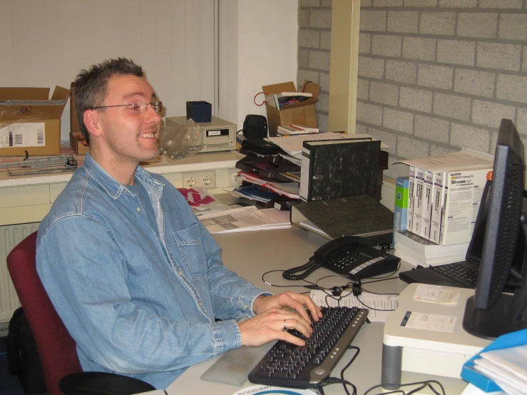 a smiling man sitting at a computer in an office