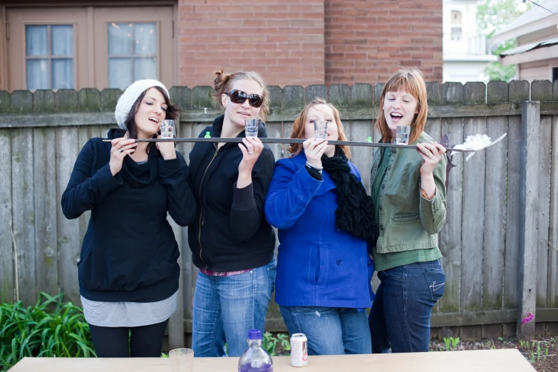 four woman standing in front of a fence holding spoons