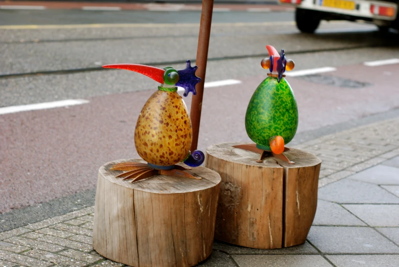 two plastic birds on wood posts on a city street