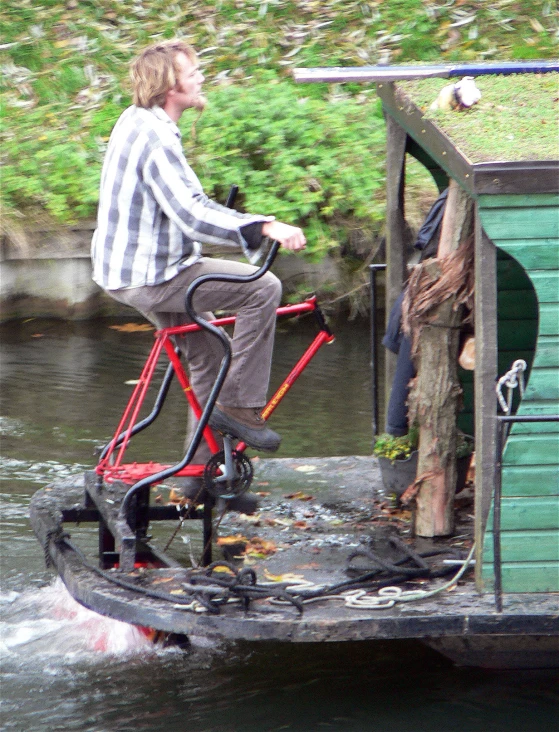 man on bike crossing over water in small boat