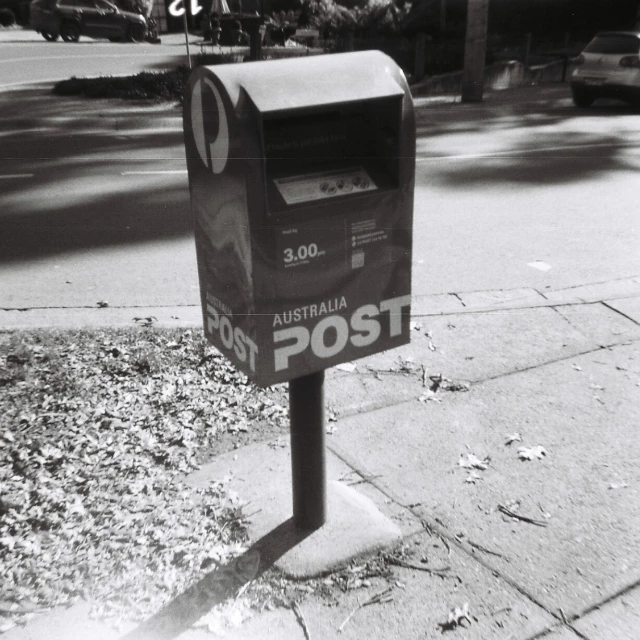 an electronic mailbox with the word post on it sitting next to the road