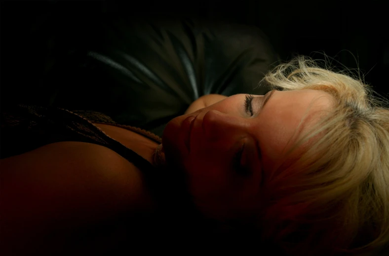 a woman laying on top of a black pillow