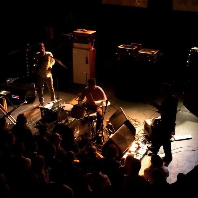 two guys are playing instruments on stage while other men sit