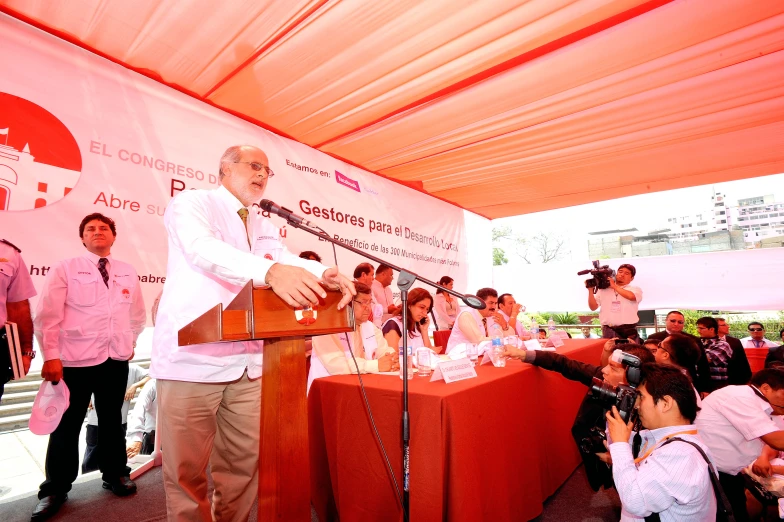 a man stands at a podium speaking into people