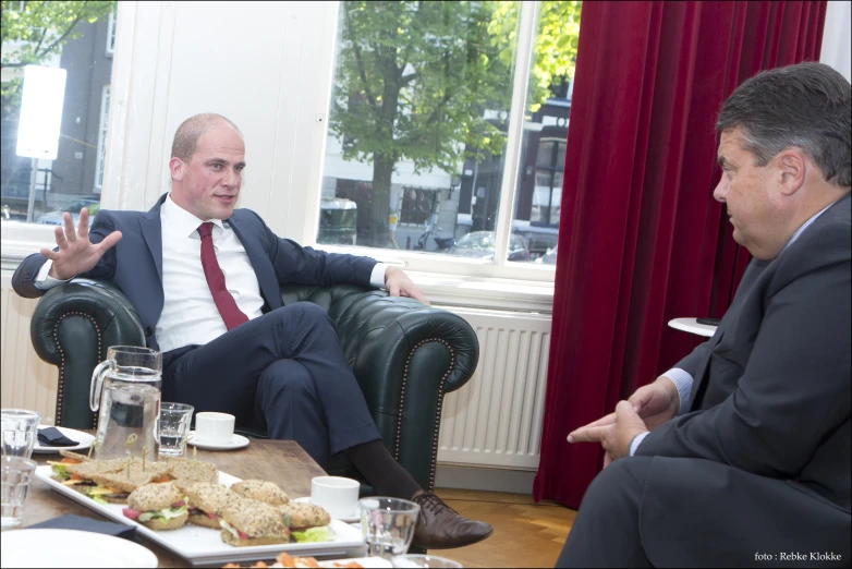 a man is sitting down while talking with another man