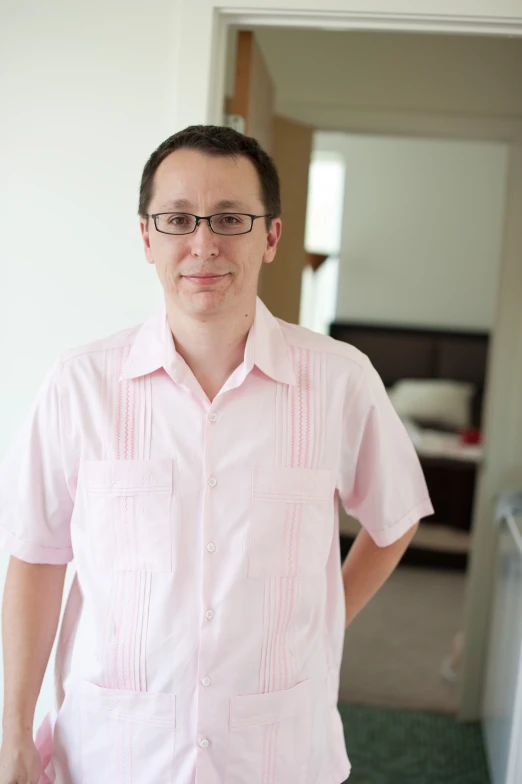 a man wearing a pink shirt standing in a room