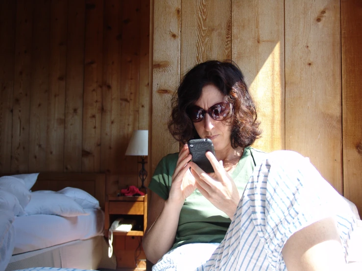 a woman is holding her phone while sitting on a bed