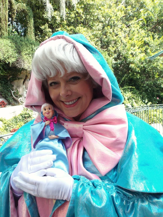 an older woman holding a doll with a blue cloak