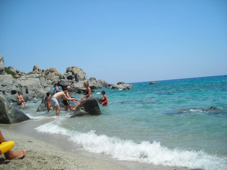 people swimming in the ocean next to rocks and rocks