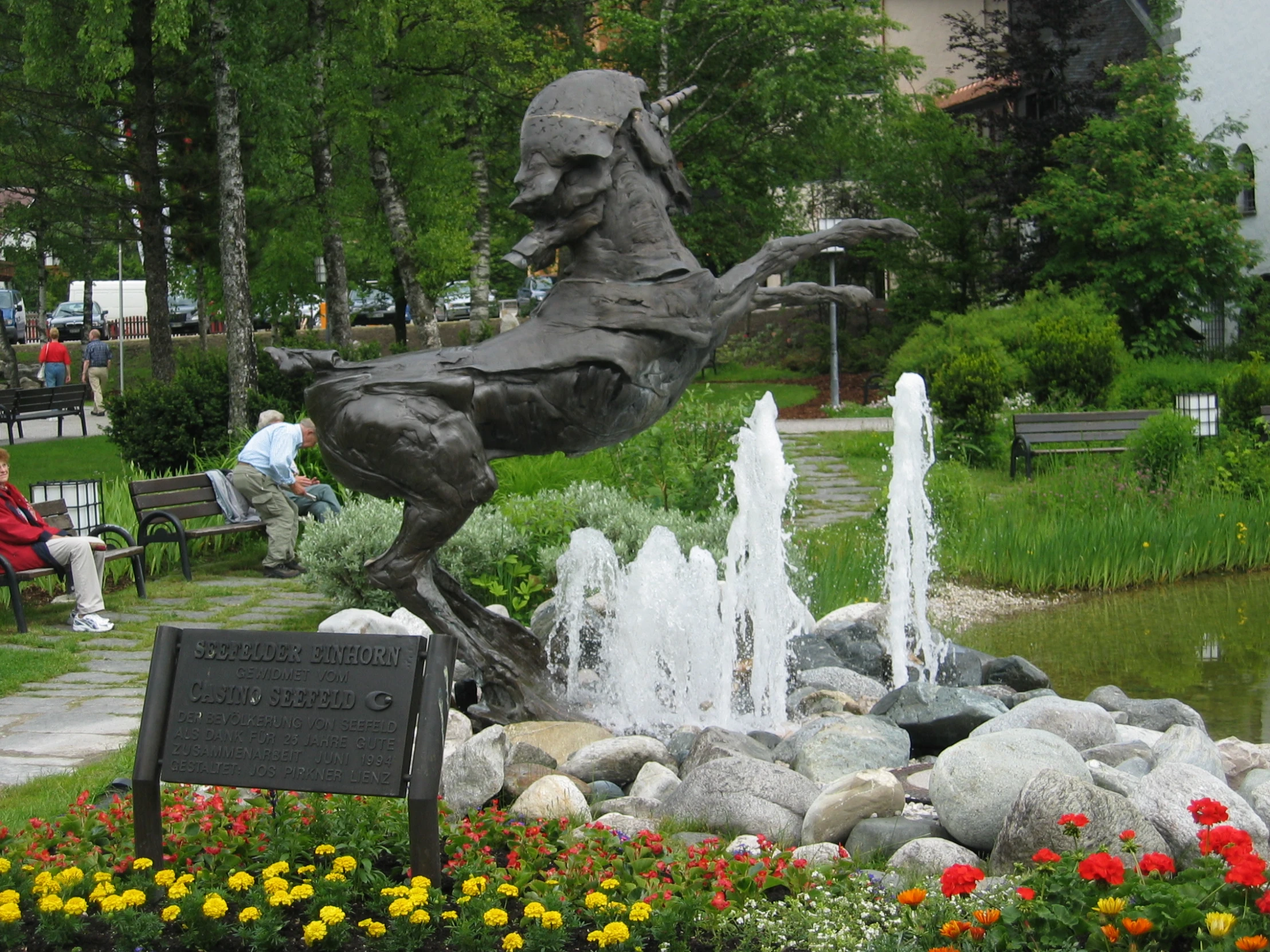 the statue is in a garden with flowers around it