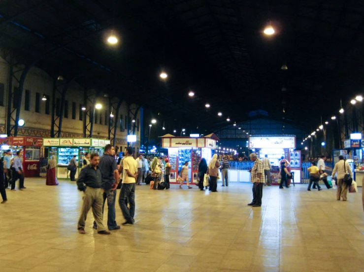 a crowded public place in the night with lots of people walking