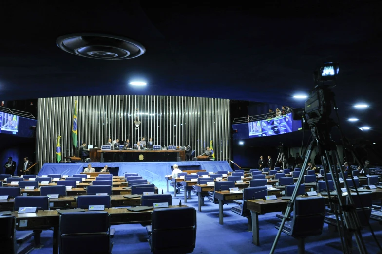 empty tables and chairs sit in front of a large screen