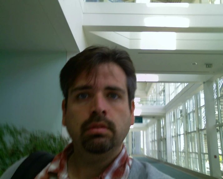 man taking selfie in hallway between buildings